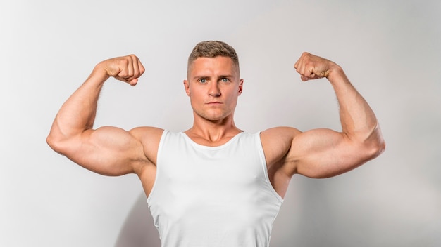 Vue de face de l'homme en forme montrant les biceps
