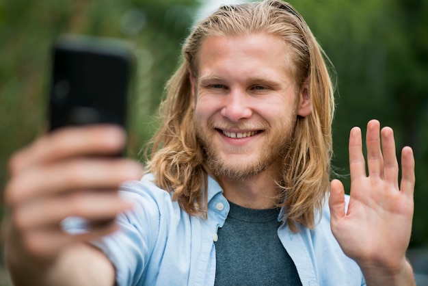 Vue de face de l'homme heureux prenant selfie à l'extérieur