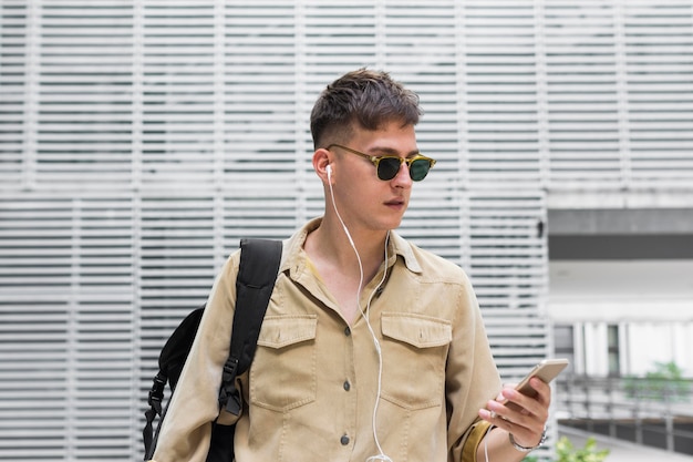 Vue de face de l'homme avec des lunettes de soleil, écouter de la musique sur des écouteurs