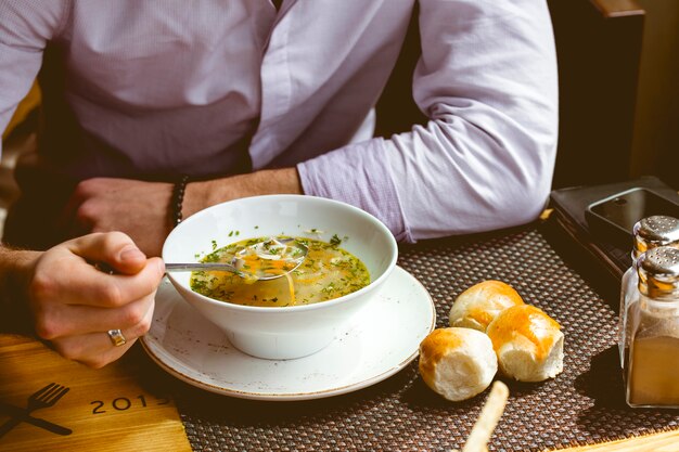 Vue de face un homme mange de la soupe au poulet avec du pain