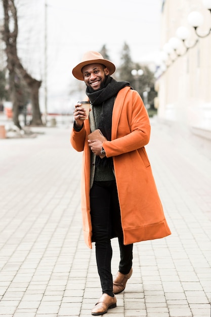 Vue de face homme en manteau orange tenant une tasse de café