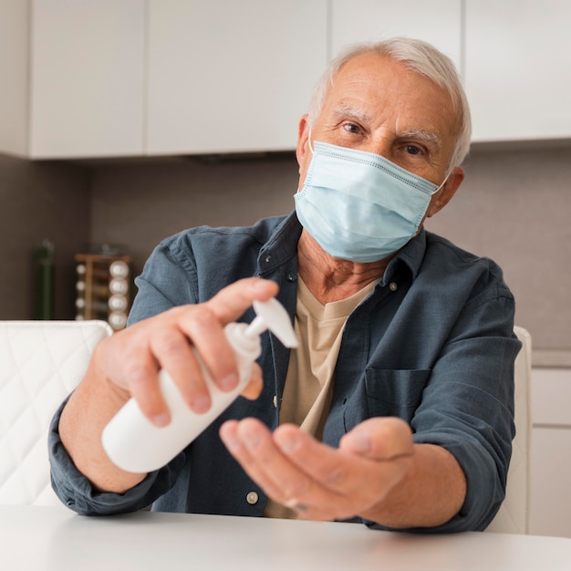 Photo gratuite vue de face homme avec masque et désinfectant