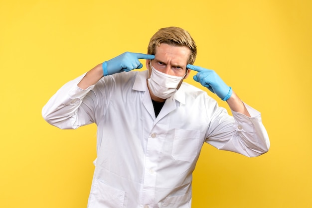 Vue de face de l'homme médecin sur fond jaune pandémie medic covid- santé