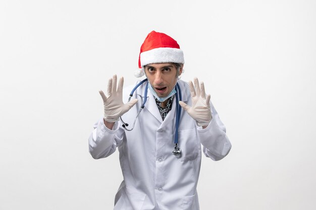 Vue de face de l'homme médecin avec des gants sur le virus mur blanc vacances covid- émotion