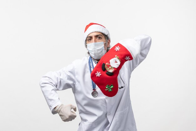 Vue de face de l'homme médecin avec grosse chaussette rouge sur le virus du mur blanc covid- vacances