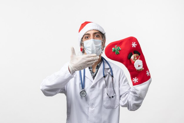 Vue de face de l'homme médecin avec grosse chaussette de vacances sur le sol blanc virus de Noël covid