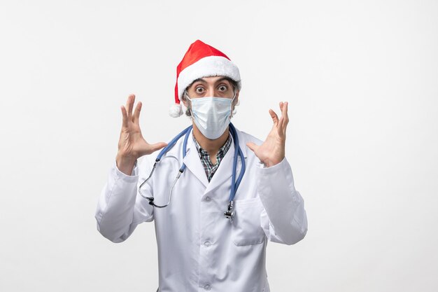 Vue de face de l'homme médecin avec masque sur bureau blanc virus pandémique covid vacances