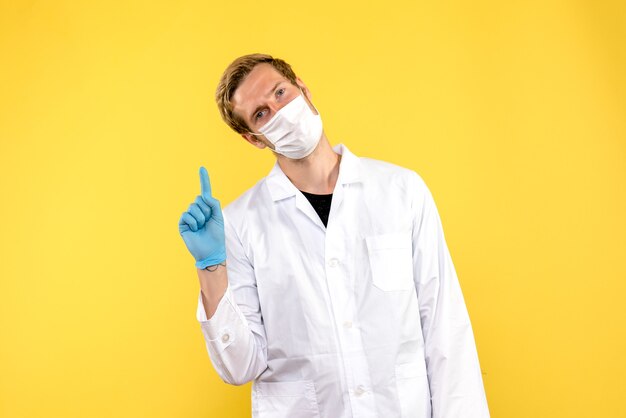 Vue de face de l'homme médecin en masque sur fond jaune pandémie médicale covid medic