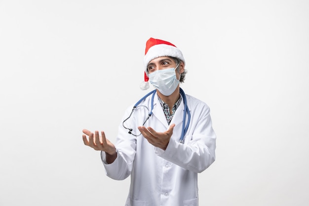 Vue de face de l'homme médecin avec masque sur un mur blanc vacances virus covid pandémique