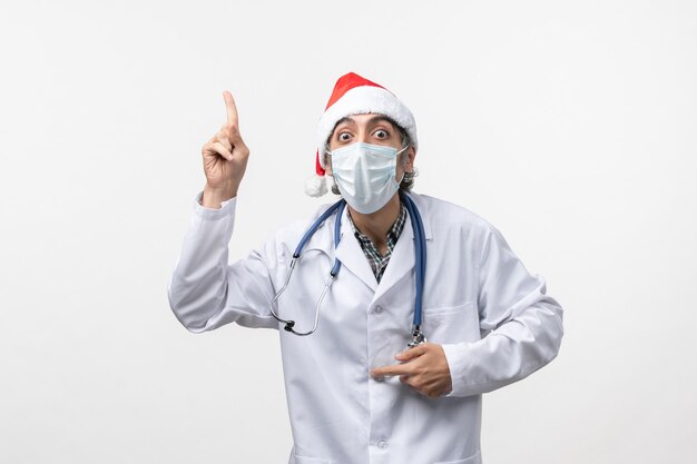 Vue de face de l'homme médecin avec masque sur mur blanc virus pandémique covid vacances
