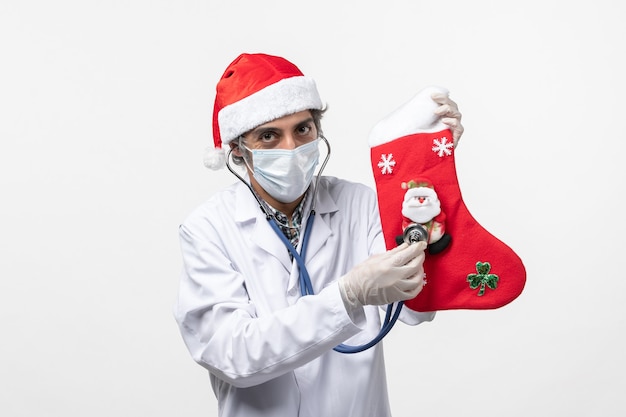 Vue de face de l'homme médecin observant la chaussette de vacances sur le mur blanc vacances virus covid