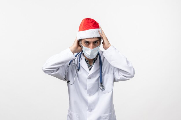 Vue de face de l'homme médecin portant une casquette rouge sur le virus mur blanc nouvelle année pandémie de covid