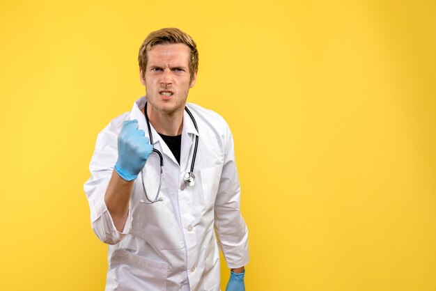 Vue de face de l'homme médecin se réjouissant sur fond jaune virus humain médical de la santé