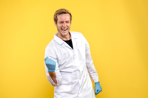 Vue de face de l'homme médecin se réjouissant juste sur fond jaune Health Medic Covid- pandémie