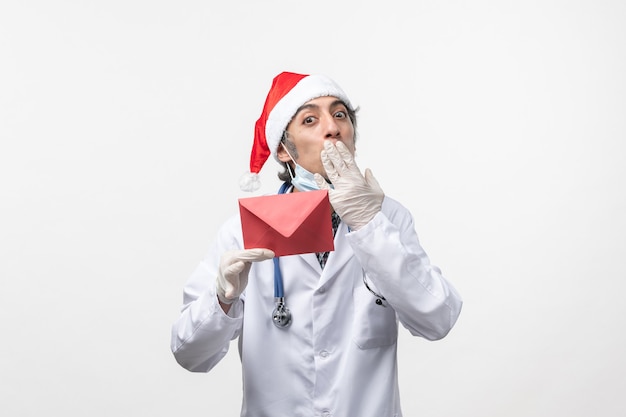 Vue De Face De L'homme Médecin Tenant Une Enveloppe Rouge Sur Un Mur Blanc Santé Covid- Virus Man