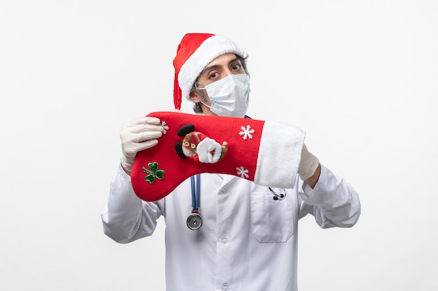 Vue de face homme médecin tenant grosse chaussette de vacances sur le bureau blanc virus covid- vacances