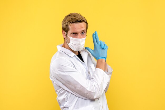Vue de face de l'homme médecin en tenue de pistolet pose sur fond jaune pandémie medic health covid-