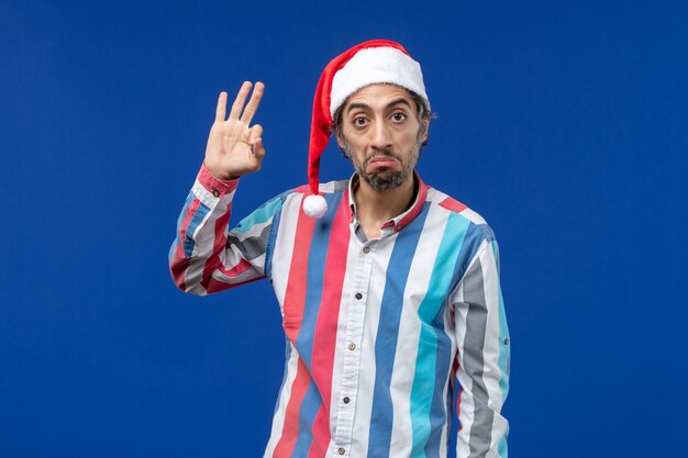 Vue de face homme ordinaire avec cape rouge sur bureau bleu vacances de noël santa mâle