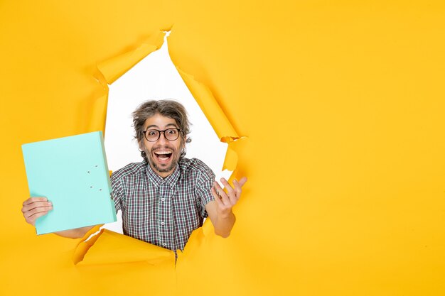 Vue de face d'un homme ordinaire avec un fichier sur un mur déchiré jaune