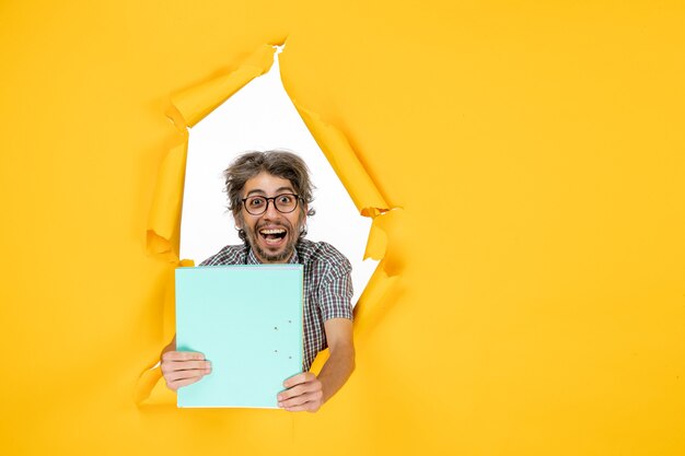 Vue de face d'un homme ordinaire avec un fichier sur un mur déchiré jaune