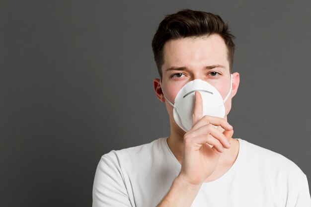 Vue de face d'un homme portant un masque médical et faisant le signe calme