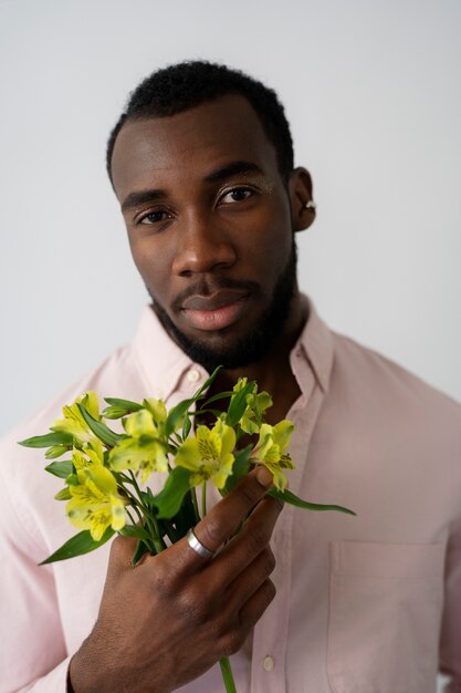 Vue de face homme posant avec des fleurs