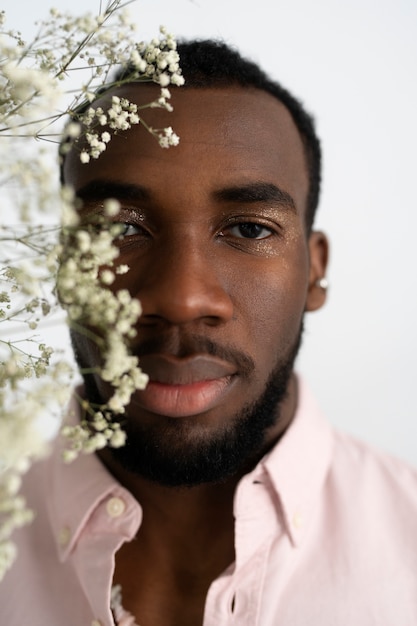 Vue de face homme posant avec des fleurs