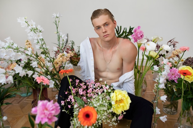 Vue de face homme posant avec des fleurs