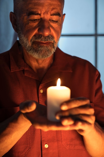 Vue de face homme senior tenant une bougie allumée