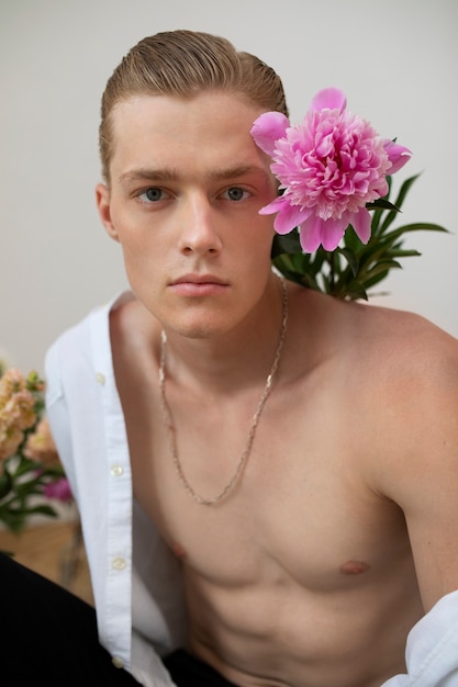 Vue de face homme sensible posant avec des fleurs