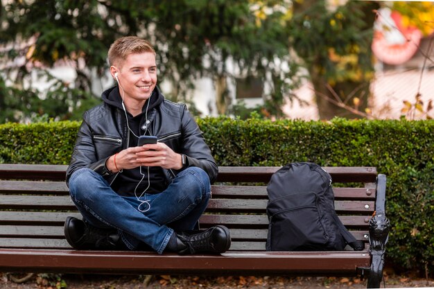 Vue de face homme souriant, écouter de la musique sur les écouteurs