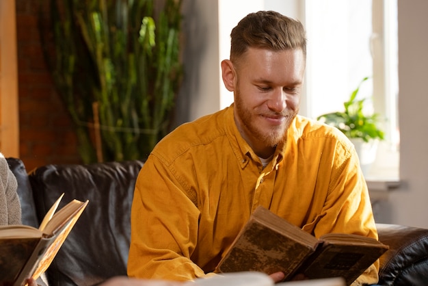 Vue de face homme souriant lisant à l'intérieur