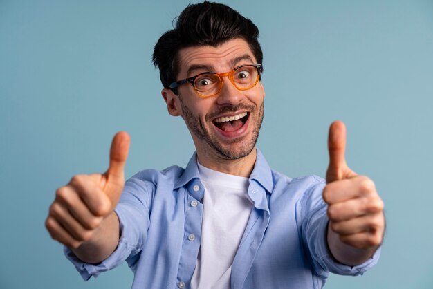 Vue de face de l'homme souriant avec des lunettes montrant les pouces vers le haut