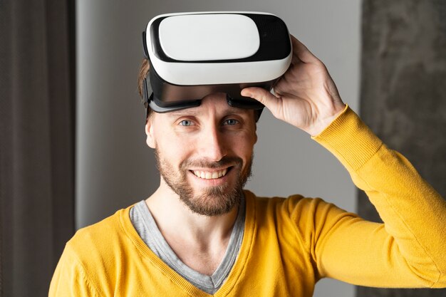 Vue de face de l'homme souriant posant avec un casque de réalité virtuelle