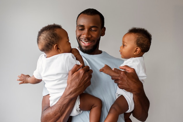 Photo gratuite vue de face homme souriant tenant des bébés