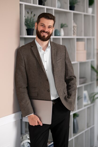 Vue de face homme souriant tenant un ordinateur portable