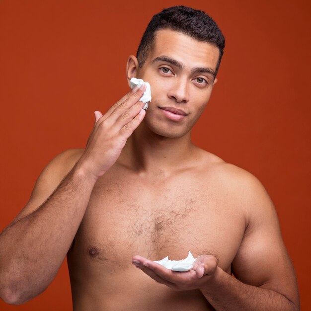 Vue de face de l'homme torse nu appliquant la mousse à raser