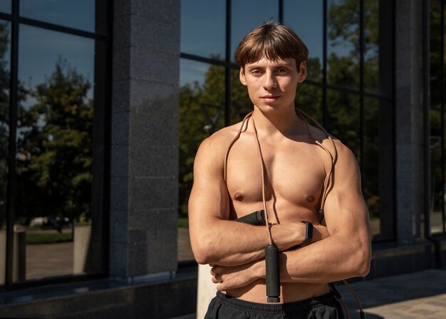 Vue de face de l'homme torse nu posant avec corde à sauter