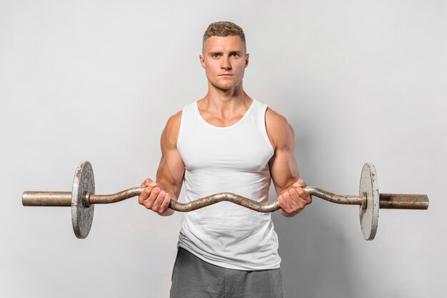 Vue de face de l'homme très en forme posant tout en maintenant des poids