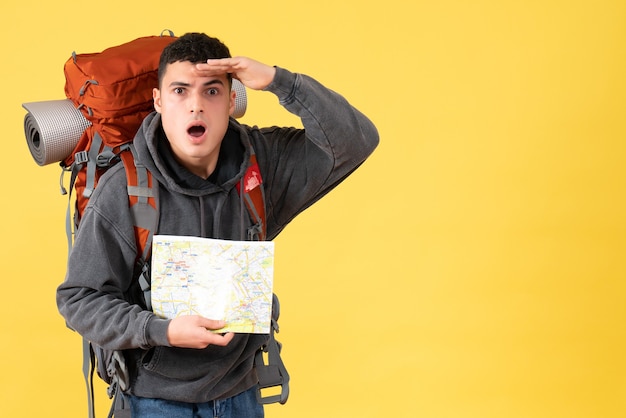 Vue de face homme voyageur étonné avec sac à dos tenant la carte