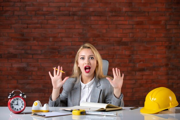 Vue de face ingénieur femme excitée assis derrière son lieu de travail