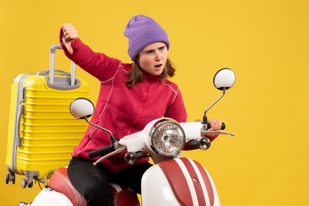 Photo gratuite vue de face insatisfaite jeune fille sur un cyclomoteur donnant le pouce vers le bas