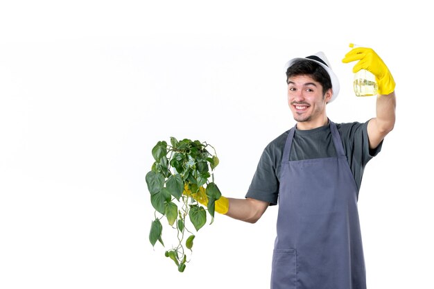 Vue de face jardinier mâle holding plante en pot et spray sur fond blanc travail arbre herbe couleur bush travail au sol jardin