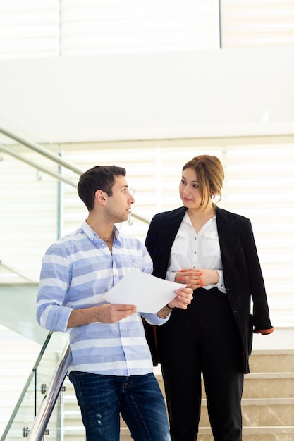 Une vue de face jeune bel homme en chemise rayée parler et discuter des problèmes de travail avec la jeune femme d'affaires au cours de l'activité de travail de jour