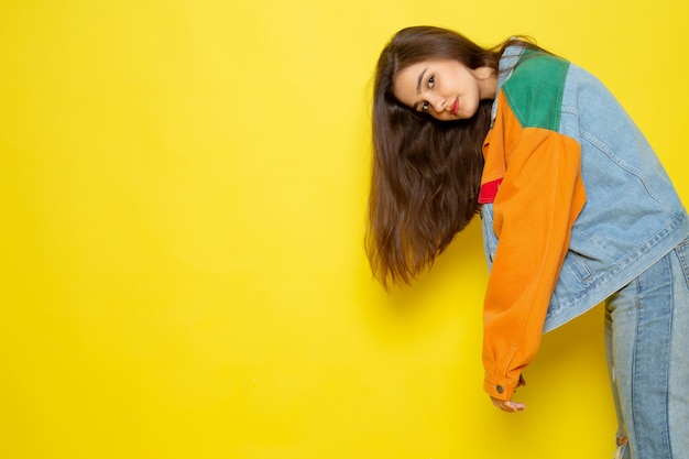 Une vue de face jeune belle dame en chemise rouge manteau coloré et blue jeans posant