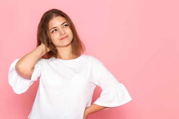 Une vue de face jeune belle femme en chemise blanche avec une expression de pensée sur son visage posant