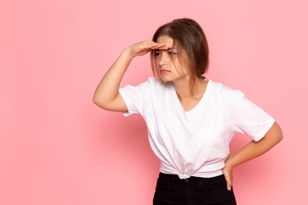 Une vue de face jeune belle femme en chemise blanche posant et regardant au loin