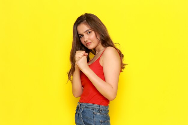 Une vue de face jeune belle fille en chemise rouge et blue-jeans boxe