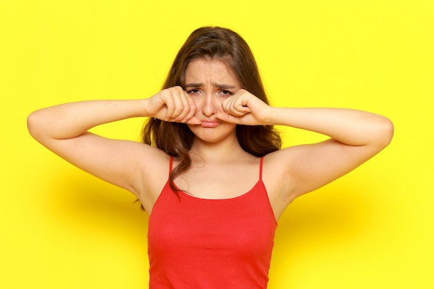 Photo gratuite une vue de face jeune belle fille en chemise rouge et jean bleu posant avec expression de pleurs