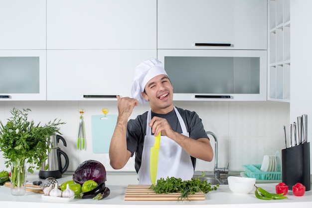 Vue de face jeune chef en uniforme pointant sur placard